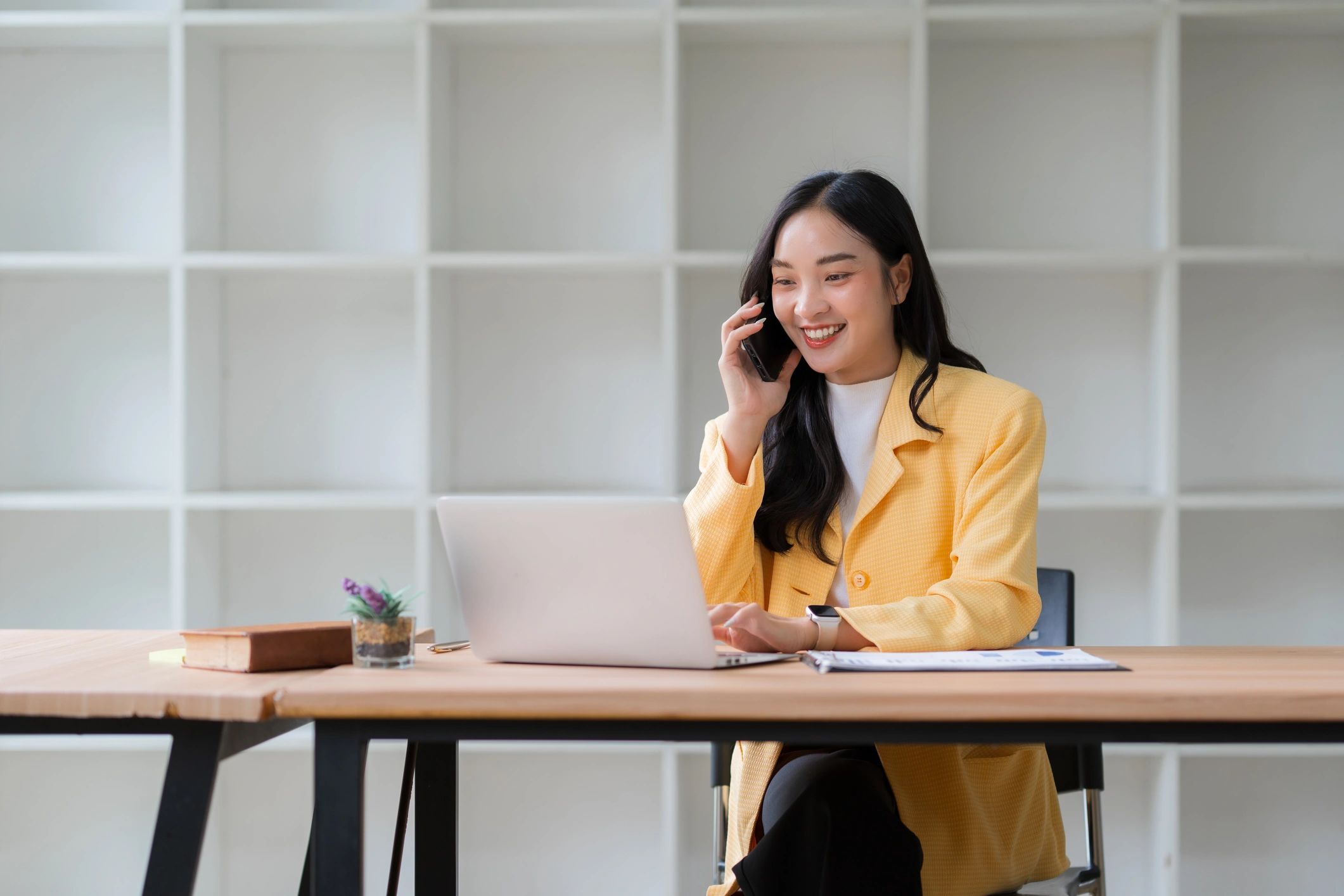 Office worker talking on phone while working on a laptop